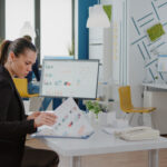 Female educator sitting in an office reviewing data reports measuring student performance on an assessment as learning task.