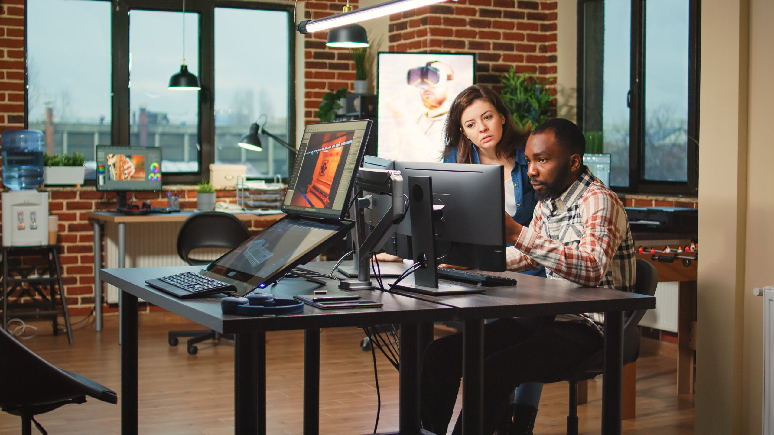 Two engineers sitting at a desk in front of computers showing interest in the implications for AI in education.